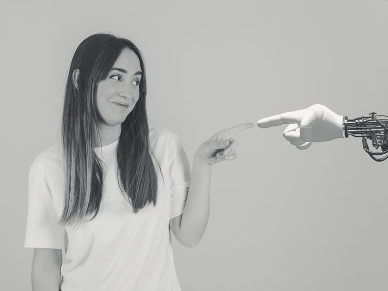 Frau und Roboterhand zeigen aufeinander